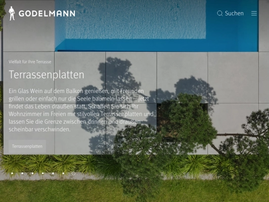 Moderne Terrassenfläche mit großen, hellen Betonplatten, darüber ein Pool und darunter Grünflächen mit Sträuchern und Gras, aus der Vogelperspektive.