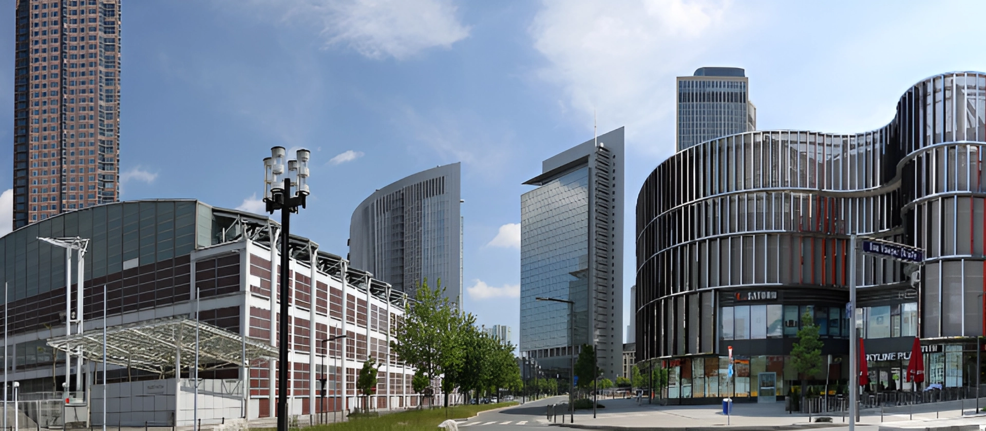 Panoramablick auf das Messegelände in Frankfurt mit modernen Glas- und Hochhausbauten, markanter geschwungener Fassade und breiter Straße unter blauem Himmel