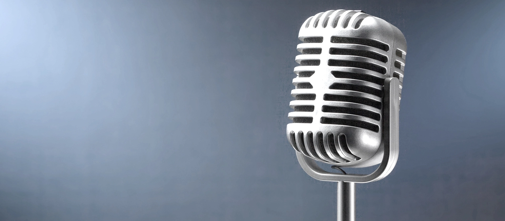 Nahaufnahme eines silbernen Retro-Mikrofons vor graublauem Hintergrund