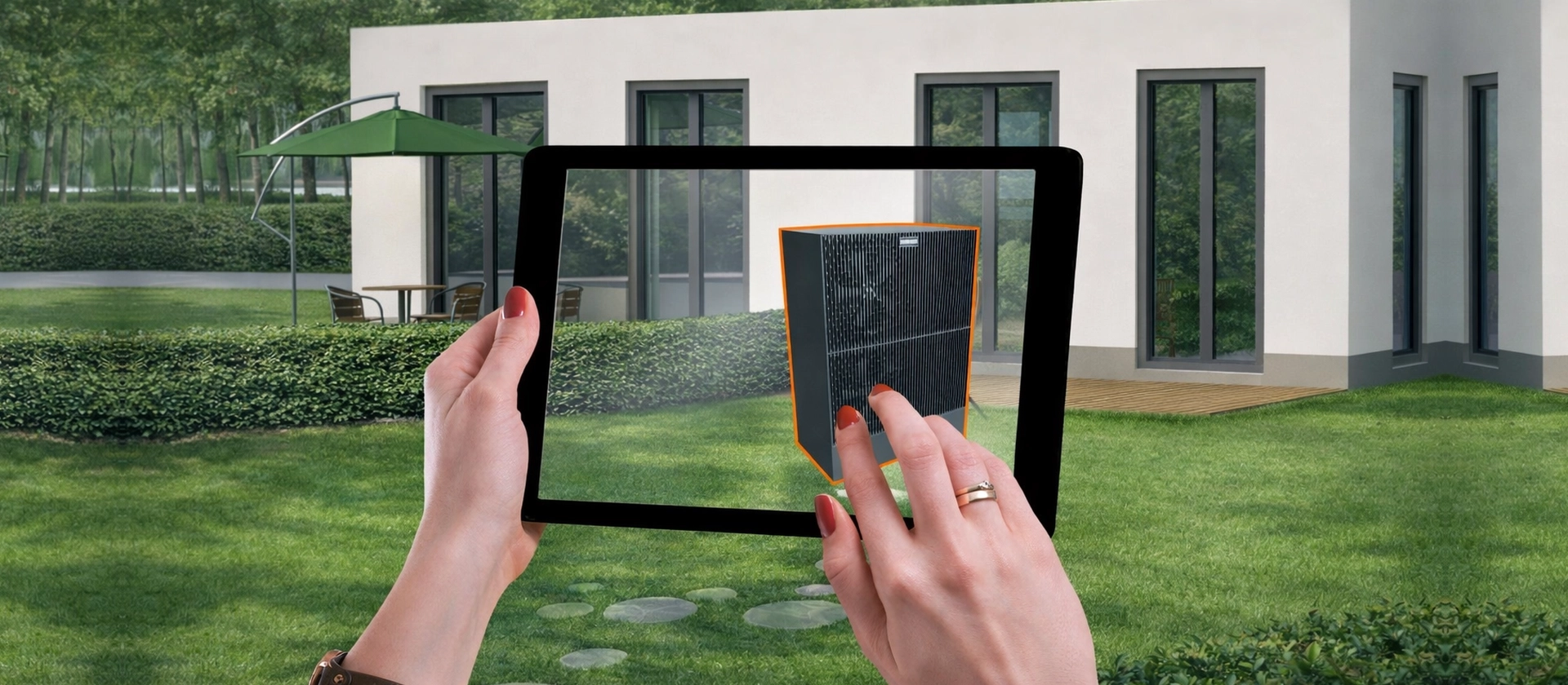 Hände halten ein Tablet im grünen Garten vor einem modernen Wohnhaus, auf dessen Bildschirm ein virtuell platziertes schwarzes Technikgerät zu sehen ist