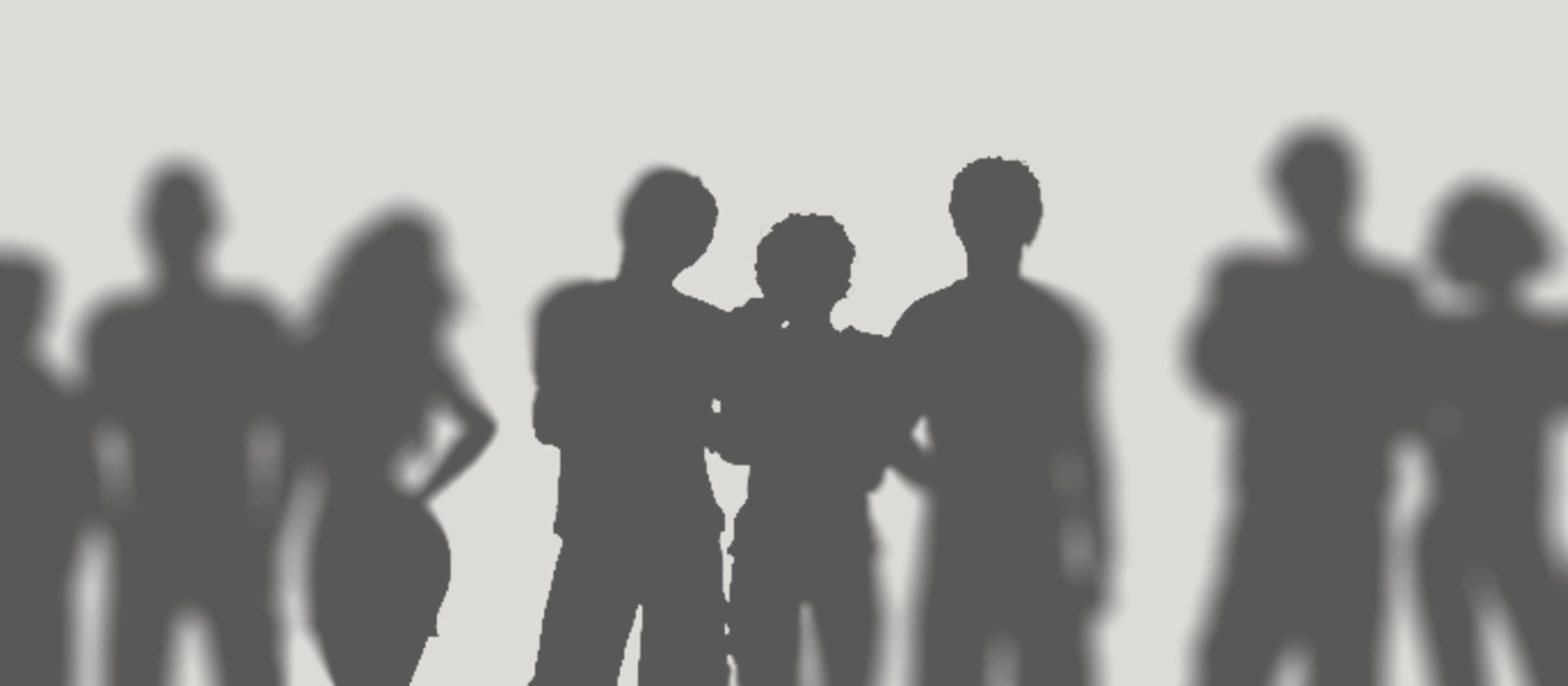 Unscharfe Silhouetten mehrerer stehender Personen vor hellem grauem Hintergrund, mittig dichter gruppiert und nach außen weich ausgeblendet, mit ruhiger, neutraler Stimmung.