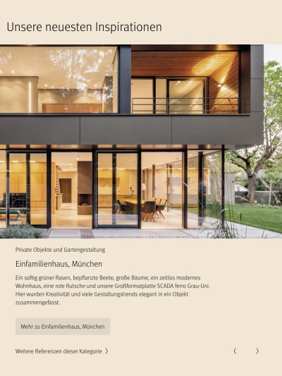 Moderner zweistöckiger Anbau aus dunklem Metall und Glas mit hell beleuchteten Innenräumen, sichtbar durch große Glasfassaden, die zu einem grünen Garten führen.