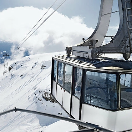 Eine Seilbahn in einer schneebedeckten Alpenlanschaft.
