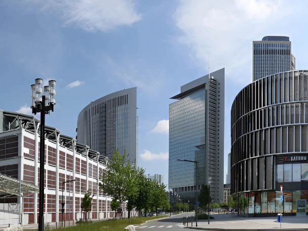 Panoramablick auf das Messegelände in Frankfurt mit modernen Glas- und Hochhausbauten, markanter geschwungener Fassade und breiter Straße unter blauem Himmel