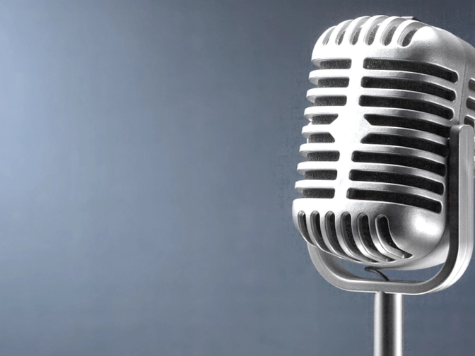 Nahaufnahme eines silbernen Retro-Mikrofons vor graublauem Hintergrund