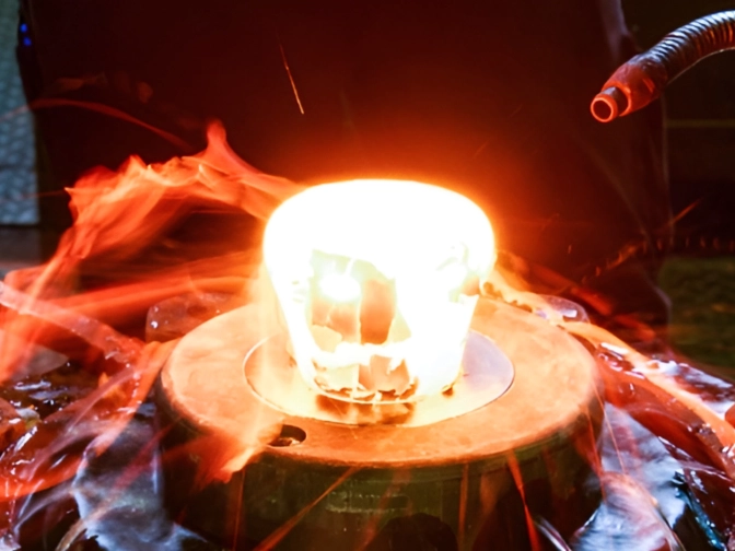 Glühend erhitztes Metallteil auf einer industriellen Schmiedevorrichtung, umgeben von Schläuchen, Schrauben und Funken in einer dunklen Werkshallenumgebung mit intensiver Hitze.