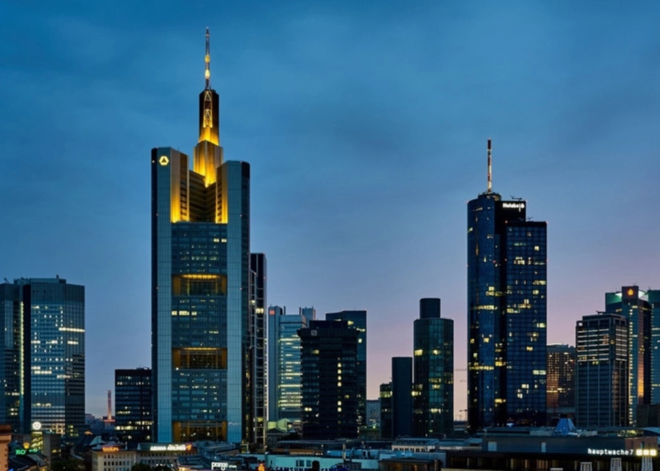 Skyline von Frankfurt am Main bei Abenddämmerung mit beleuchteten Hochhäusern. Im Mittelpunkt der Commerzbank Tower.